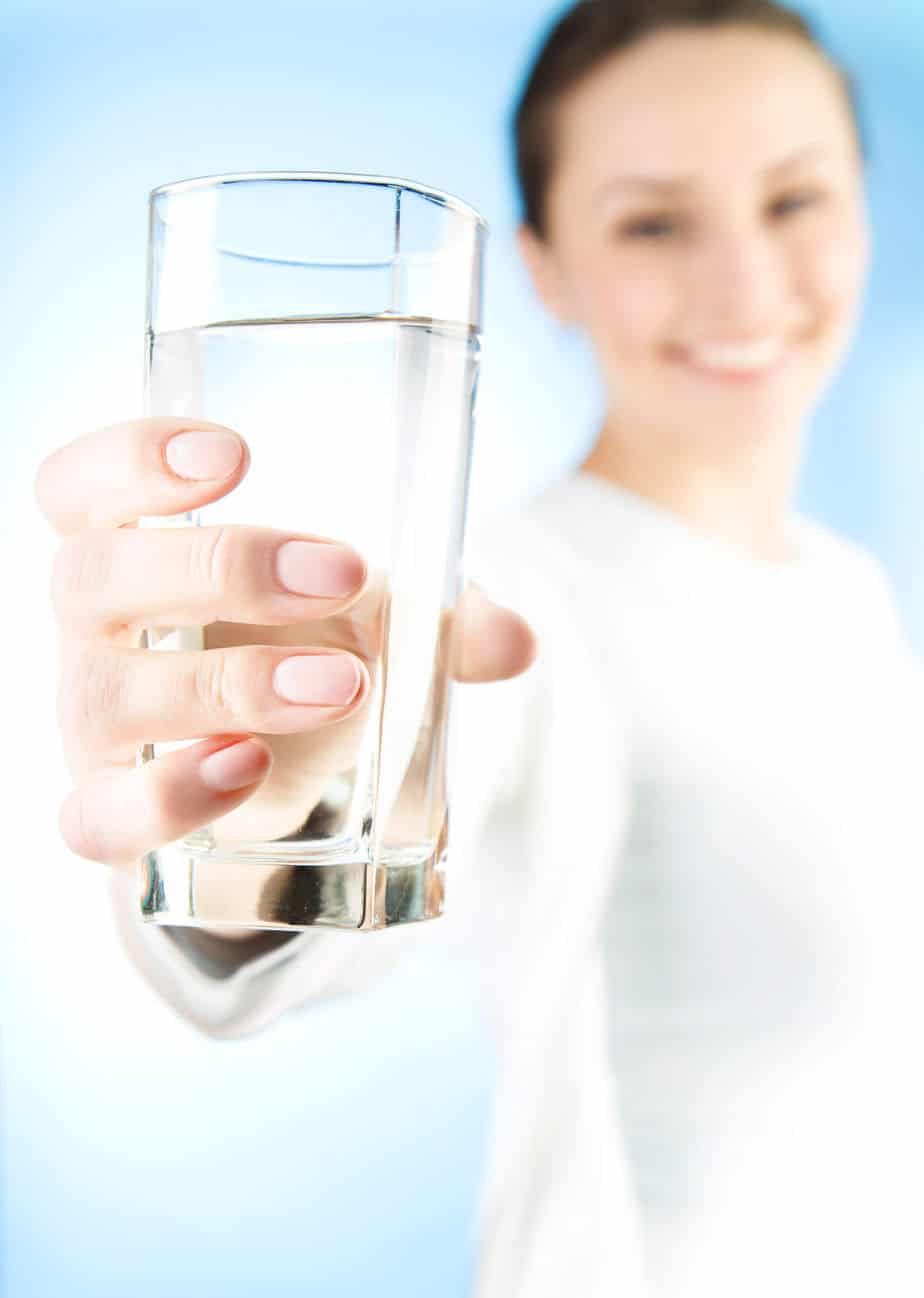 Woman holding a glass of water.  Drinking water is important for weight loss with intermittent fasting.